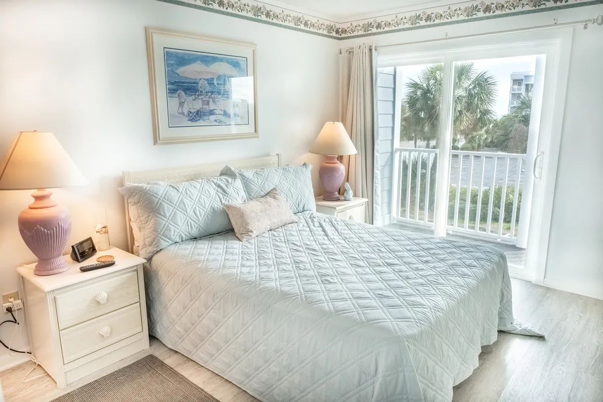 A serene bedroom with a neatly made bed, soft lamps on either side, and a window letting in natural light. The space feels restful and welcoming, with a tranquil ambiance perfect for unwinding.