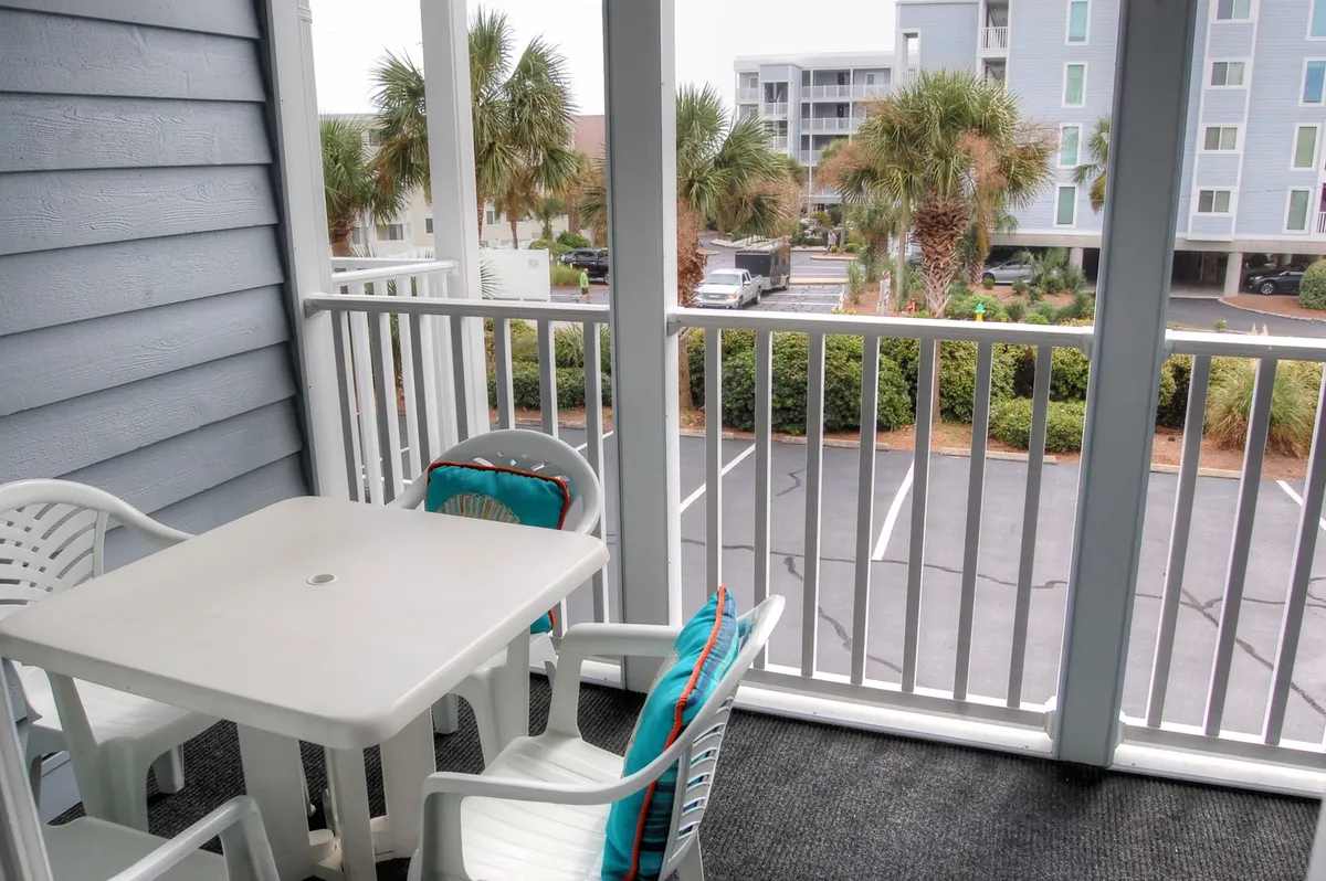 This image shows an exterior table and chairs set amid palm trees near a parking area, evoking the experience of outdoor dining or leisurely relaxation with resort landscaping in the background. The casual setup and visible natural elements reinforce the sense of enjoying semi-private outdoor spaces.